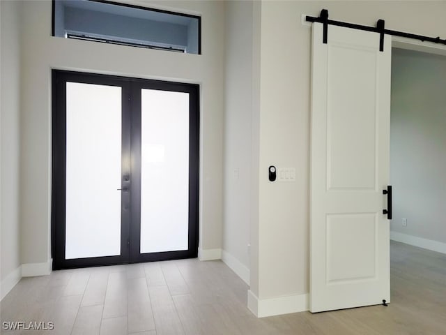 entrance foyer with light wood finished floors, baseboards, an AC wall unit, and french doors