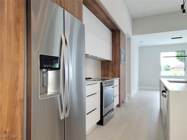 kitchen with a sink, white cabinetry, light countertops, appliances with stainless steel finishes, and modern cabinets