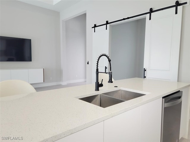 kitchen featuring light stone counters, a barn door, white cabinetry, a sink, and modern cabinets