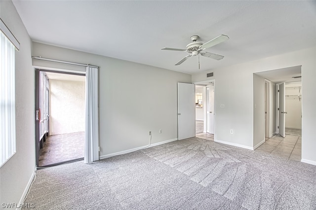 unfurnished bedroom featuring a closet, light colored carpet, and ceiling fan