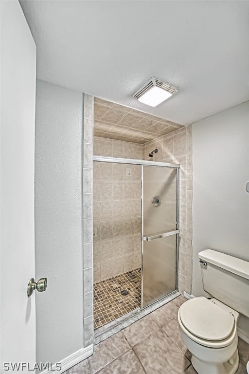 bathroom with tile patterned flooring, toilet, and walk in shower