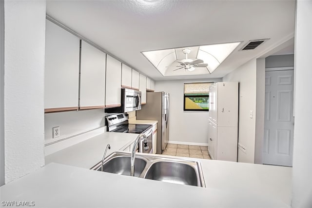 kitchen featuring white cabinetry, sink, ceiling fan, light tile patterned floors, and appliances with stainless steel finishes