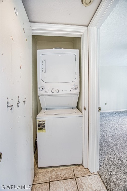 washroom featuring stacked washer / drying machine and light carpet