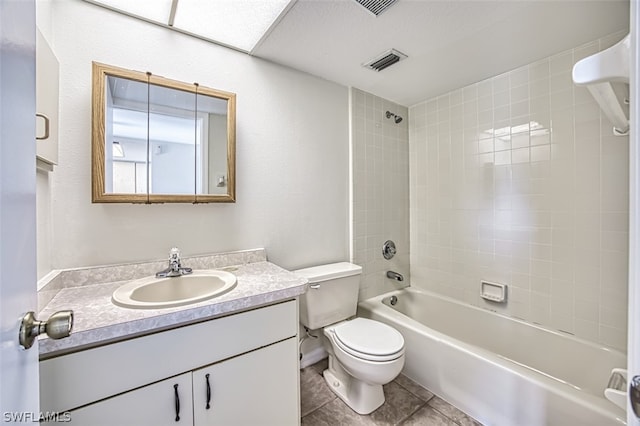 full bathroom featuring tile patterned flooring, tiled shower / bath combo, toilet, and vanity