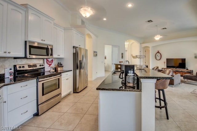 kitchen featuring white cabinets, dark stone counters, light tile patterned floors, and appliances with stainless steel finishes