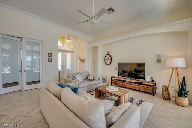 tiled living room with ceiling fan with notable chandelier, crown molding, and french doors