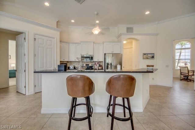 kitchen with white cabinets, light tile patterned floors, stainless steel appliances, and a kitchen island with sink