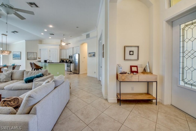 living room featuring vaulted ceiling, light tile patterned flooring, and ceiling fan with notable chandelier