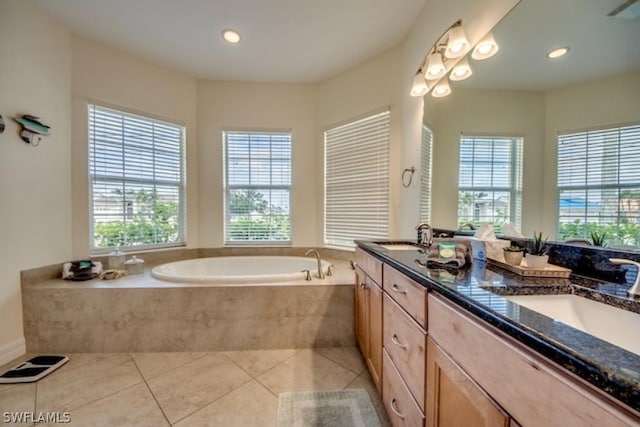 bathroom featuring tile patterned flooring, vanity, and tiled bath