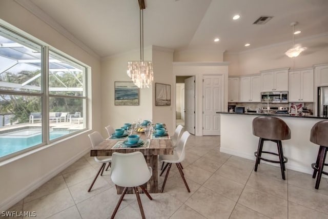 tiled dining space with a chandelier, crown molding, and vaulted ceiling