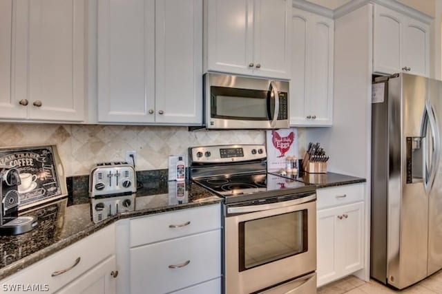 kitchen featuring white cabinets, dark stone countertops, light tile patterned floors, and stainless steel appliances