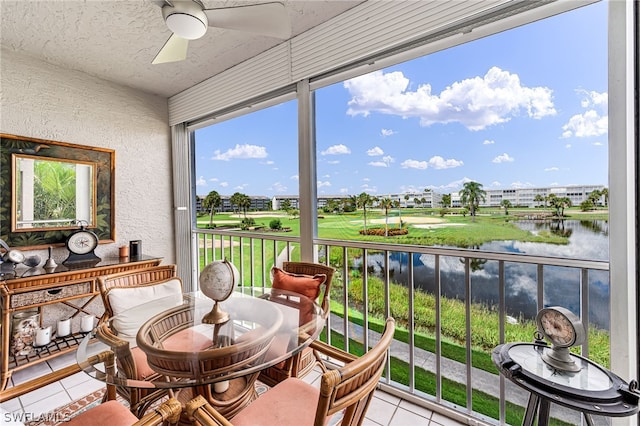 sunroom / solarium featuring ceiling fan and a water view