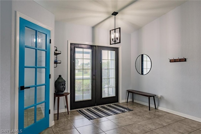 tiled foyer featuring french doors and an inviting chandelier