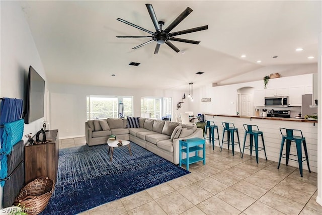 living room featuring ceiling fan, light tile patterned floors, and vaulted ceiling