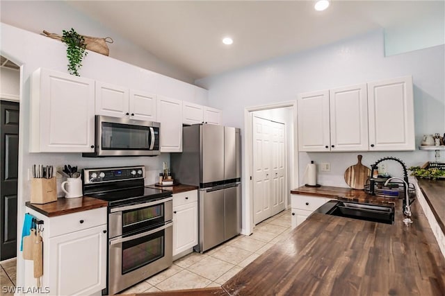 kitchen with stainless steel appliances, butcher block countertops, white cabinetry, and sink