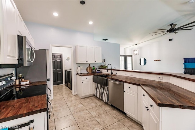 kitchen featuring kitchen peninsula, white cabinets, wooden counters, and appliances with stainless steel finishes