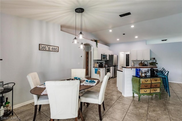 dining area with vaulted ceiling and light tile patterned flooring