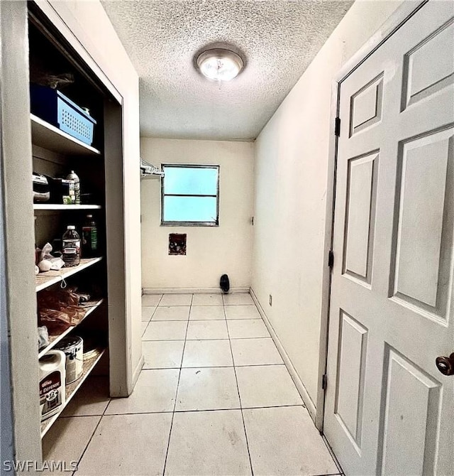 hallway with light tile patterned floors and a textured ceiling