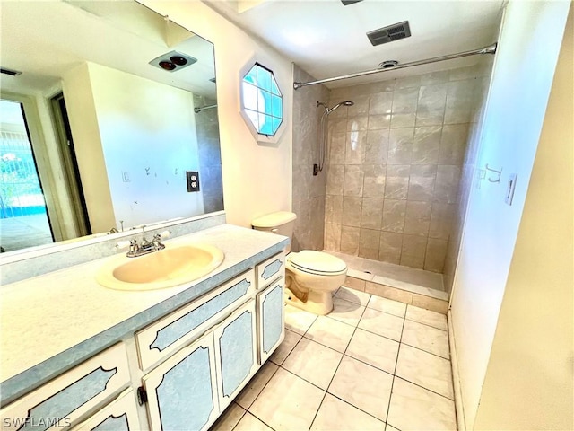 bathroom featuring tile patterned flooring, vanity, toilet, and a tile shower