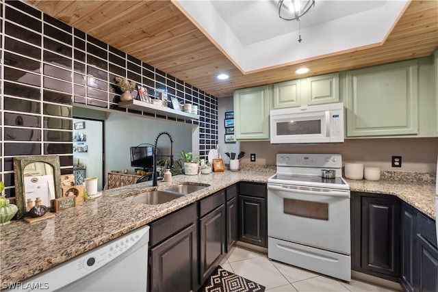 kitchen with light stone countertops, white appliances, sink, light tile patterned floors, and green cabinetry