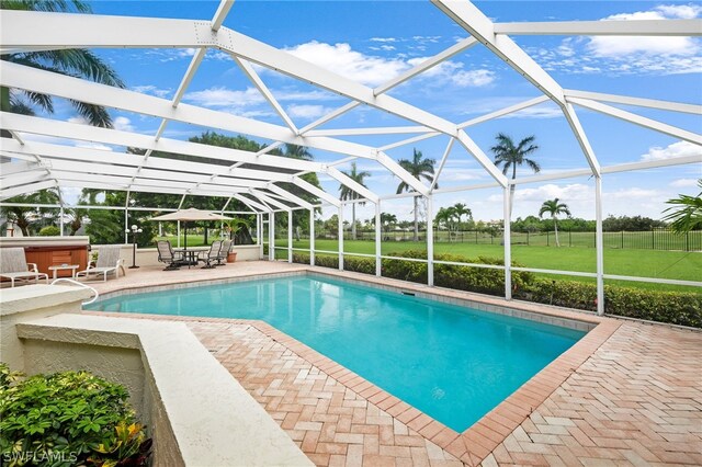 view of pool with a hot tub, a lanai, a patio area, and a lawn