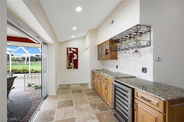 kitchen with dark stone counters, sink, wine cooler, vaulted ceiling, and decorative backsplash