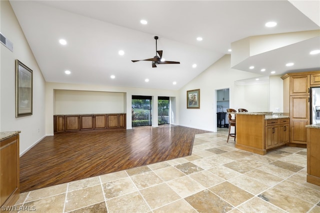 unfurnished living room with ceiling fan, high vaulted ceiling, and light hardwood / wood-style flooring