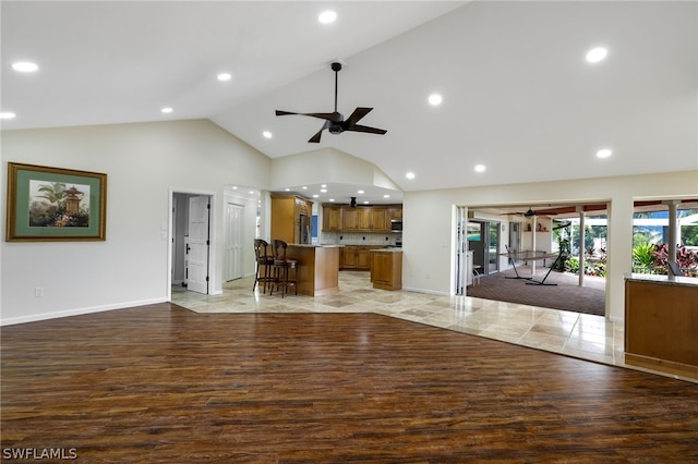 unfurnished living room with ceiling fan, wood-type flooring, and high vaulted ceiling