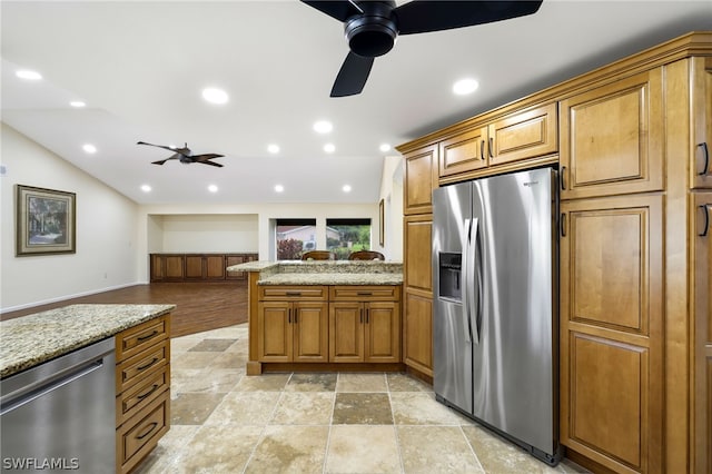 kitchen featuring light stone counters, kitchen peninsula, stainless steel appliances, and light hardwood / wood-style flooring