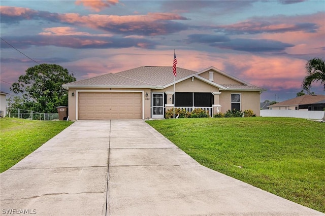 ranch-style home featuring a garage and a yard