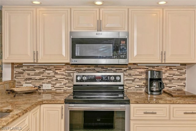 kitchen featuring light stone countertops, cream cabinetry, stainless steel appliances, and tasteful backsplash