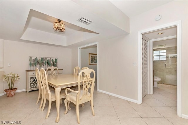 tiled dining space with a raised ceiling