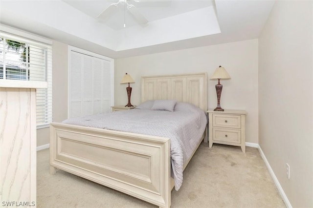 bedroom with a tray ceiling, ceiling fan, and light colored carpet