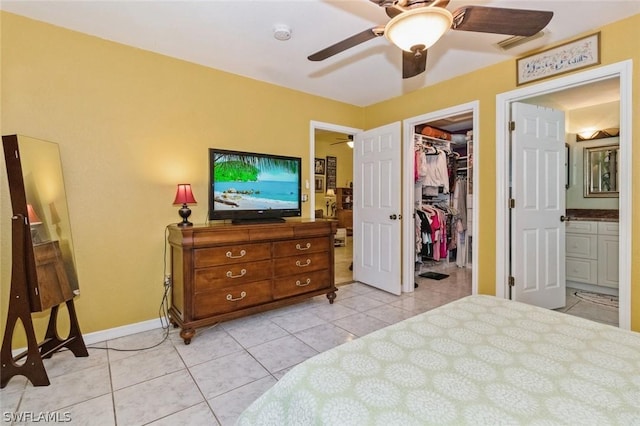 bedroom featuring ensuite bath, ceiling fan, light tile patterned floors, a spacious closet, and a closet