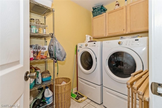 laundry area with washing machine and dryer, light tile patterned flooring, and cabinets