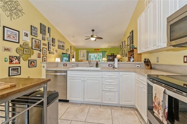 kitchen featuring kitchen peninsula, stainless steel appliances, white cabinetry, and sink