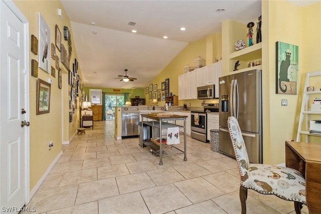 kitchen featuring ceiling fan, lofted ceiling, a kitchen bar, a kitchen island, and appliances with stainless steel finishes