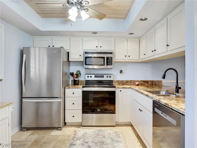 kitchen with stainless steel appliances, a raised ceiling, white cabinetry, and sink