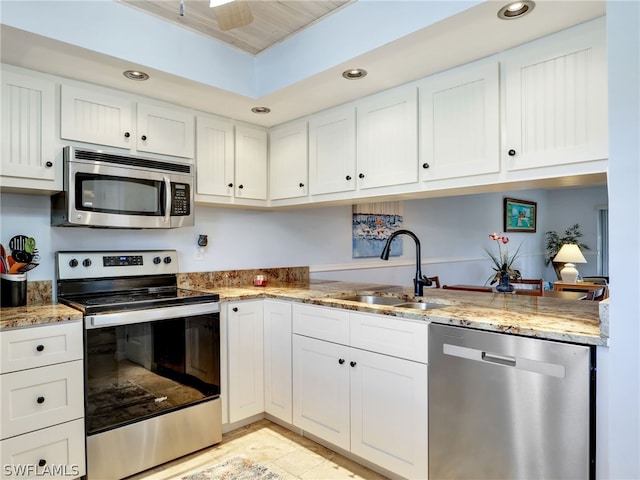 kitchen with light stone countertops, appliances with stainless steel finishes, white cabinetry, and sink