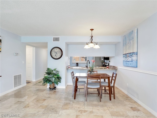 dining room featuring sink, a textured ceiling, and a chandelier