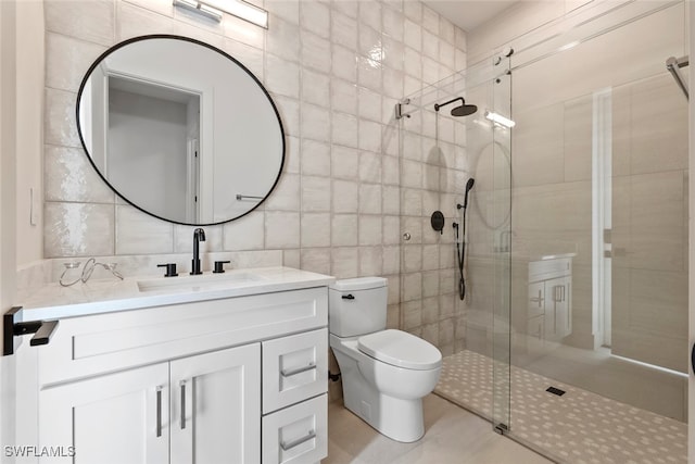 bathroom with vanity, a shower with door, tile walls, tile patterned flooring, and toilet