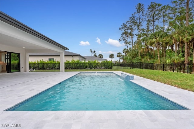 view of swimming pool with pool water feature, a yard, and a patio