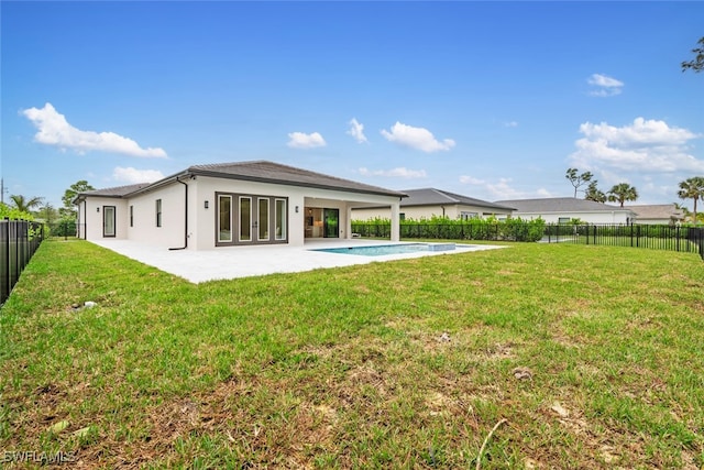 rear view of house with a fenced in pool, a yard, a patio, and french doors