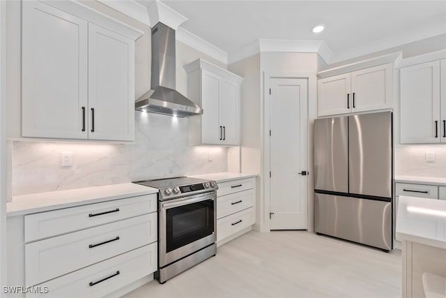 kitchen featuring decorative backsplash, white cabinetry, wall chimney exhaust hood, and appliances with stainless steel finishes