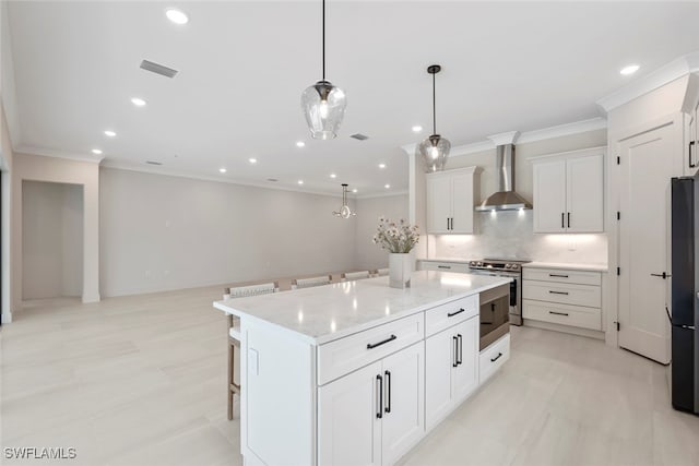 kitchen with a breakfast bar, stainless steel electric stove, wall chimney range hood, white cabinets, and hanging light fixtures