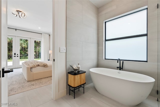 bathroom with tile patterned floors, a bathtub, french doors, and tile walls