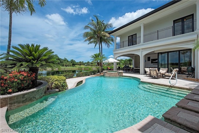 view of pool with an in ground hot tub, a water view, and a patio