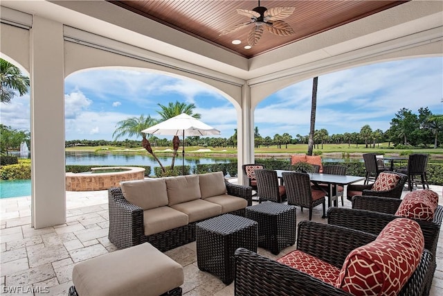 view of patio with an in ground hot tub, an outdoor hangout area, a water view, and ceiling fan