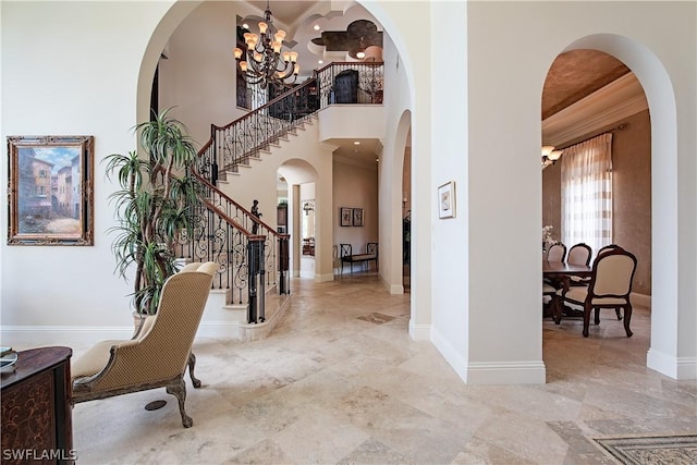 foyer entrance featuring ornamental molding, a high ceiling, and a notable chandelier