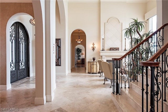 entrance foyer with french doors, a towering ceiling, and a notable chandelier